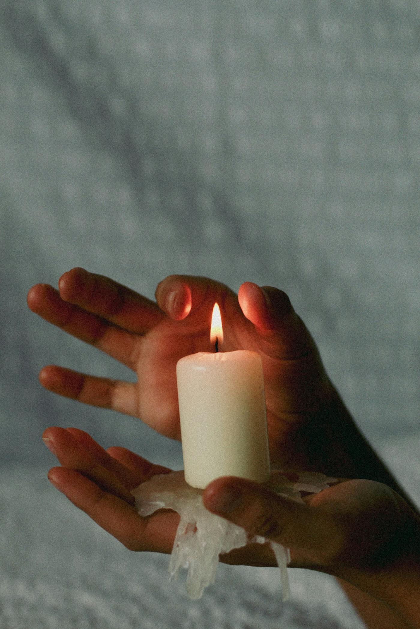 Hands holding a lit candle in quiet reflection