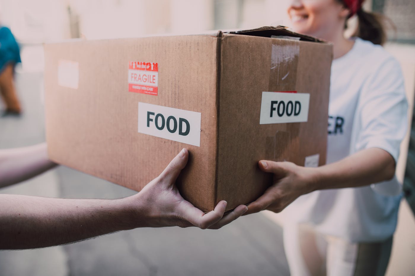Hands passing a donation box marked food