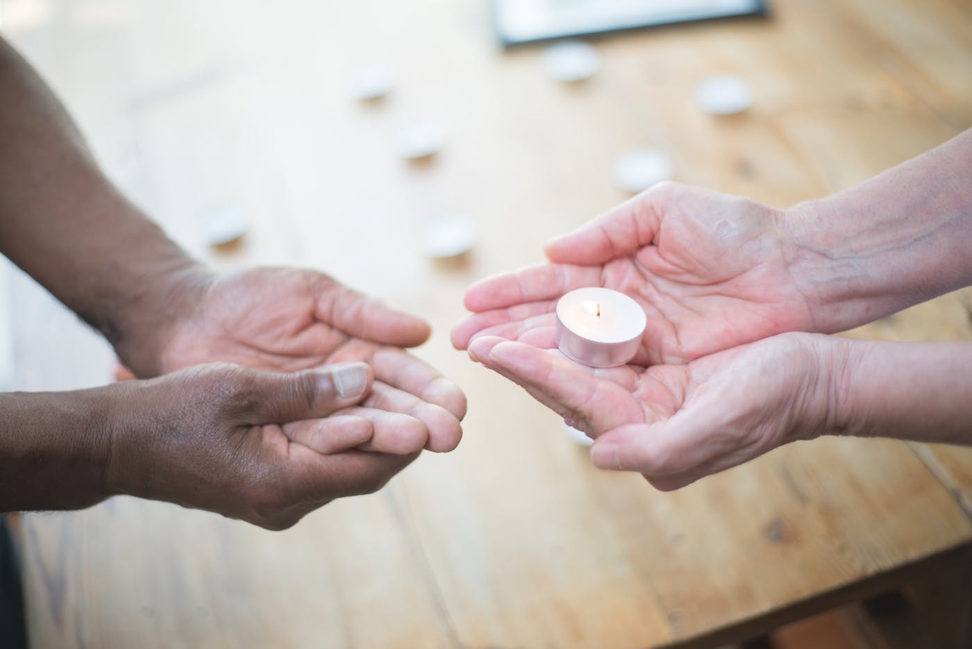 Two hands sharing a small candle as a symbol of trust and connection